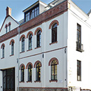 Foto: Das ganze weiße Haus vom Fundament bis zum Dach über Eck. Linksseitig Eingang vom Parkplatz. Rechtsseitig Eingang von Strasse.